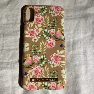 iPhone X/XS skal  - Superfint ideal of sweden skal till iPhone X/XS som är beige/gult, med blommor, kvistar och fåglar på. Inga repor eller sprickor på. Priset är lite dyrare pga att det är dyrare att köpa. Skickar med postnords frakt 15kr. Postbevis✅