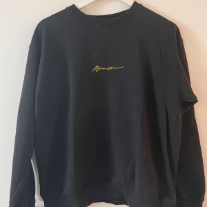 Svart sweatshirt med tryck - Svart sweatshirt med guld tryck från mennace. Använt en del men är ändå i bra skick. Sitter väldigt bra och är någorlunda tunn.