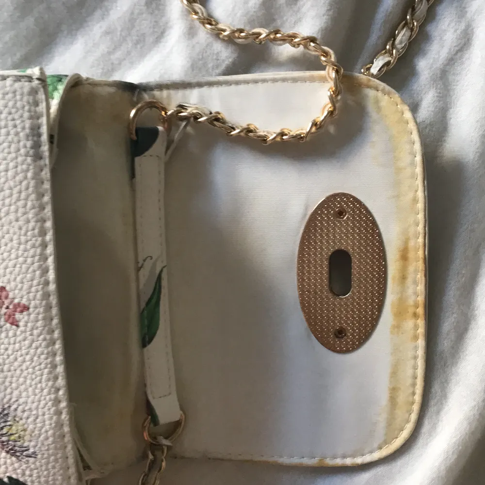 Säljer nu min vit blommiga handväska, är lite smutsig (se bild 3). Vet inte riktigt vart den är ifrån, men det finns en ”logga” inuti kontakta mig för att se bild, men jag tror att det är typ Glitter.. Laukut & Käsilaukut.