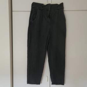Svarta jeans från H&M i storlek 40. Högmidjade och 98 cm långa från midjan till benets slut. Innerbenslängden är ca. 65 cm. Fickor både fram och bak. Dragkedja och 2 knappar i fram. 
