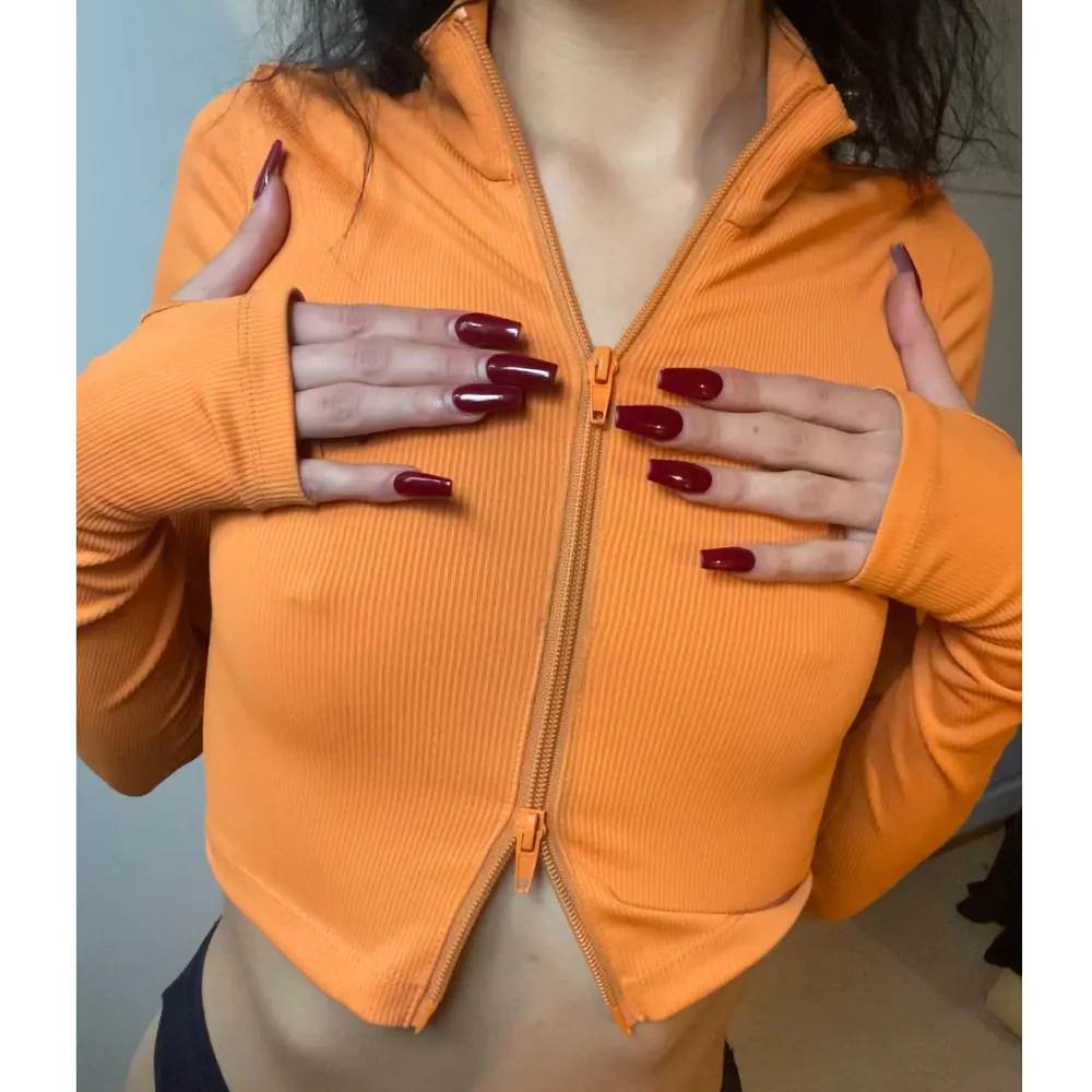Skitsnygg ribbad orange långärmad tröja med tumhål samt dragkjedja man kan öppna från båda hållen, vilket gör att man kan bära denna tröjan på olika sätt🤩  . Toppar.