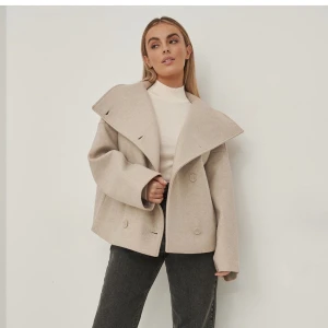 Beige kort kappa - Säljer denna beigea kappa ifrån NA-KD i storlek 34, helt ny med alla lappar kvar, helt slutsåld🤍