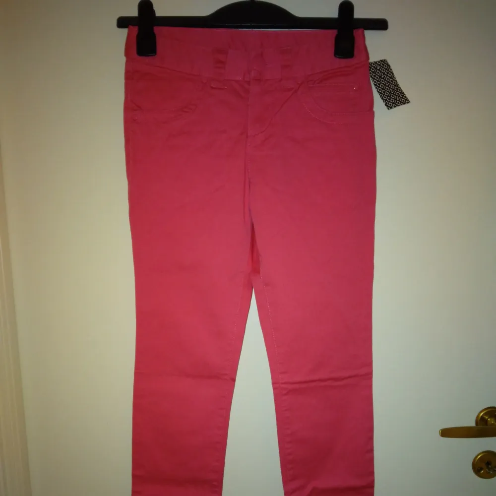 Helt nya och oanvända neonrosa/cerisa smala/slim fit byxor. Storlek: 32/XS. Materal:  Bomull. Lappar/tags sitter kvar sedan inköpet. Har fickor fram+bak och hällor för skärp. Helt felfria. Nypris i butik var 198 kr.. Jeans & Byxor.