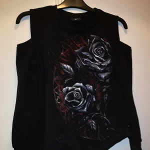 Topp med rosor  - En topp med rosor fram. Hel svart bak, med öppna axlar. Sneskuren nedtill. I fint skick. 