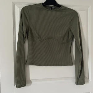 Topp - En militärgrön ribbad topp med sömdetalj.