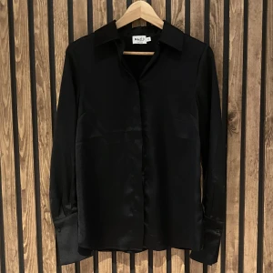 NA-KD blus 32 - Säljer en skjorta/blus i satin från NA-KD i storlek 32, men är oversized så passar från 32-36 beroende på hur man vill ha den. Aldrig använd. 