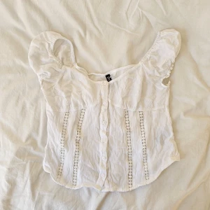 Dekorerad vit topp - Knappt använd vit topp från H&M. Luftig och skönt tyg. Jättegullig men passar inte mig.