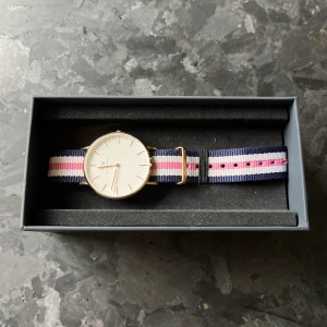 Daniel Wellington  - En Daniel Wellington klocka i roséguld med ett rosa och blått band. Är näst intill oanvänd, alltså i nyskick. 