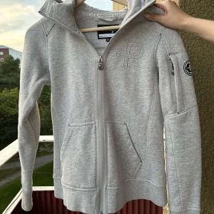 Hoodie med dragkedja  - Pelle Petterson Hoodie med dragkedja, färg grå. Bra skick.