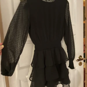 Svart klänning i mesh och textur  - Superfin klänning med volangkjol, mesh i ryggen