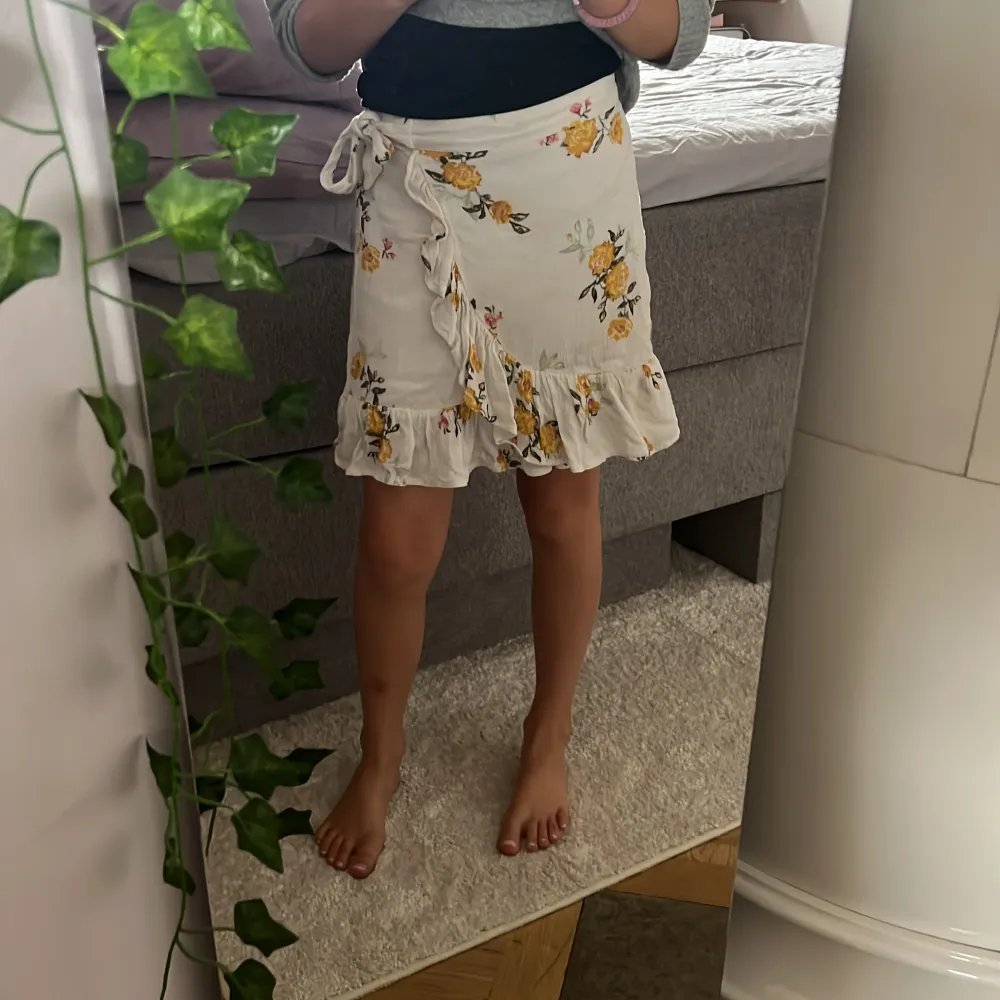 Det är en fin vit kjol med gula blommor på, det finns några små rosa blommor på också. kjolen har 2 snören så du kan knuta den om det behövs. 🌼☀️🌸. Kjolar.