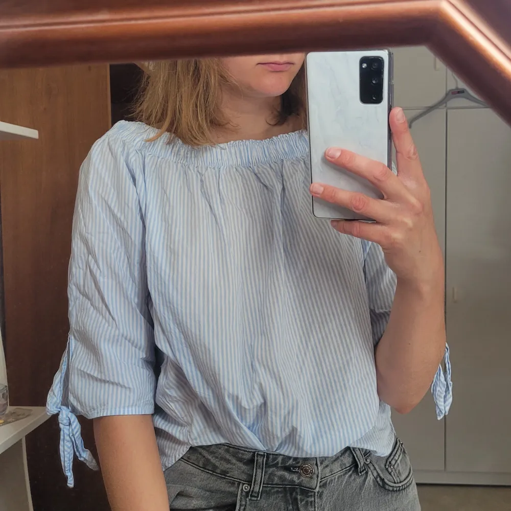 Offshoulder topp som är blå och vit randig, med knyten på armarna. Går även att använda som en vanlig topp utan offshoulder (som på bilden). Materialet är 100% bomull. 52 cm lång. Använd några få gånger. . Toppar.