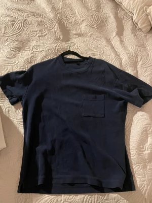 Blå t shirt - Mörkblå t shirt med en ficka på bröstet. Från Uniqlo