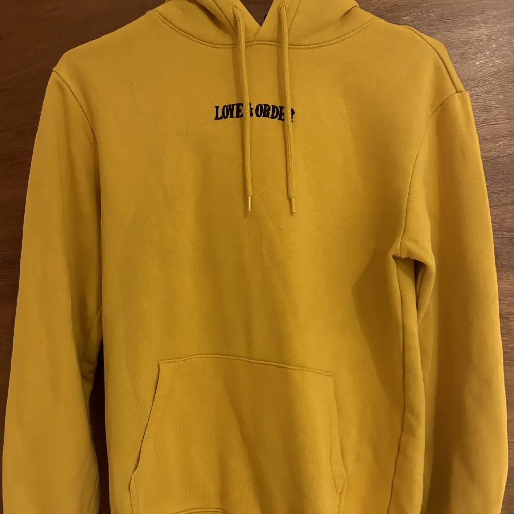 En gul/orange jätte fin hoodie med text ”love and order” och som har ett coolt tryck på ryggen!. Hoodies.