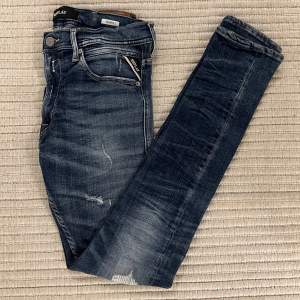 Säljer dessa Replay jeans i modellen Jondrill som liknar Anbass, slim fit. De är i en snygg tvättat blå färg med fräscha slitningar! Storleken är W31L31. Nypris: ca 1850kr, Mitt pris: 499kr! Hör av er vid frågor eller funderingar!