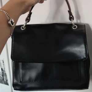 Liten skinnväska - En liten svart väska i mycket gott skick med många fack! Går att ha som axelremsväska eller knäppa av remmen och ha som handväska.