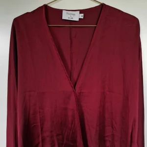 Röd satinblus med vida ärmar - Använd endast en gång - nyskick! Röd satinblus från NA-KD. Löst sittande med vida ärmar - väldigt smickrande för alla figurer.