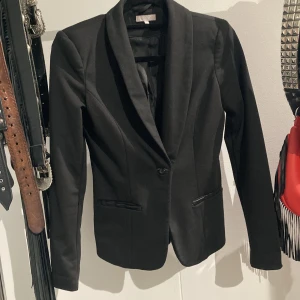 Kavaj med supersnygg form - Kavaj, lite formsydd med snygga skinndetaljer på fickorna. Säljer endast för att den har blivit för liten för mig.  Superfin passform. Använd enstaka gånger. S. Köpare betalar frakt. 