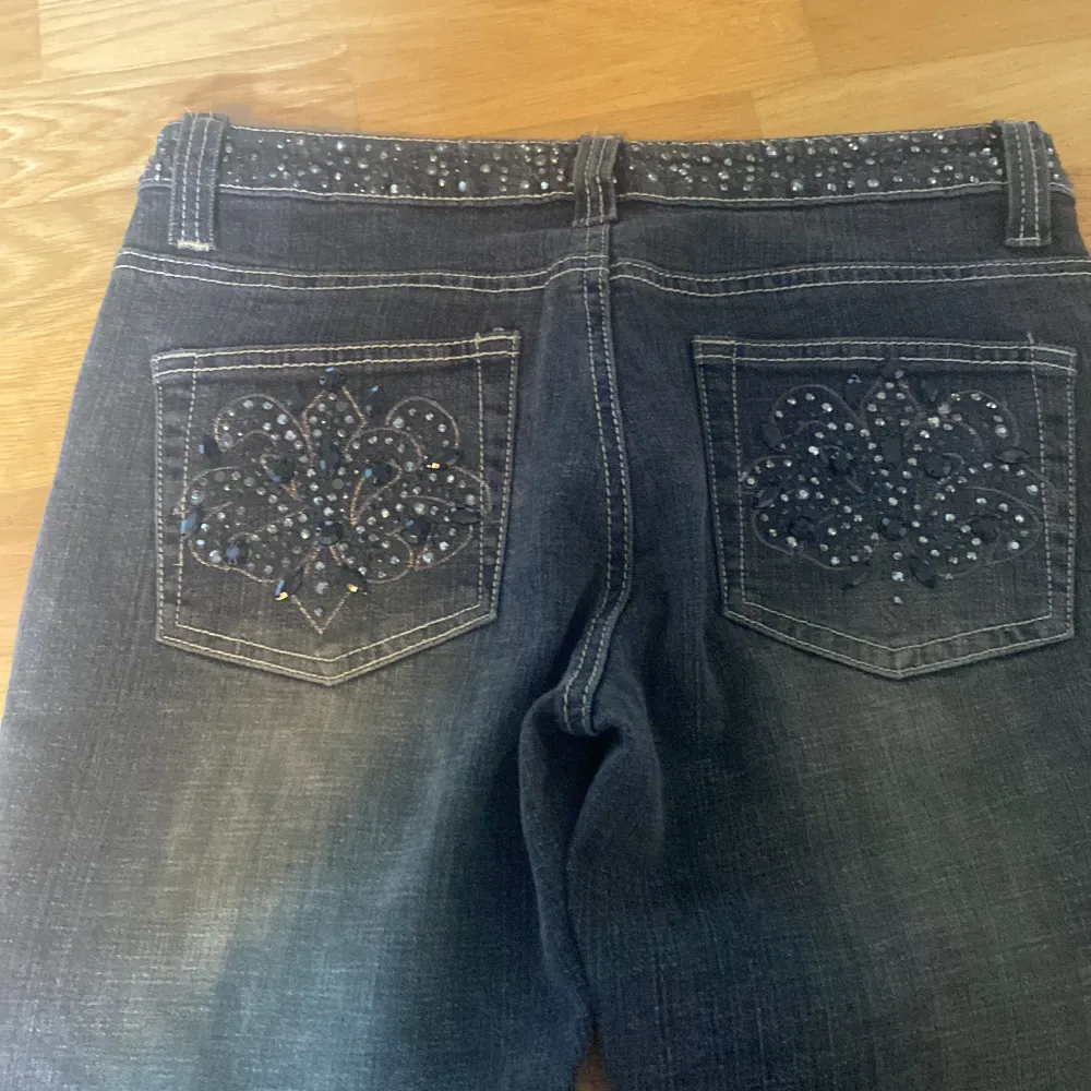 Säljer dessa fina svarta jeans med detaljer fram och bak. Köpte ifrån Vinted men är bara testade 1 gång. De är i modellen boot/flare. I sten har lossnat där fram men det är inget man tänker på!. Jeans & Byxor.