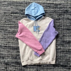 Hoodie med broderi - Hoodie från H&Ms MTV-kollektion. Jättecoola färger och tryck, riktiga retro/90tals vibbar. Tyvärr inte riktigt min stil längre :(. Använd en del och lite urtvättad men inga defekter annars. Hör av dig med frågor eller intresse!!