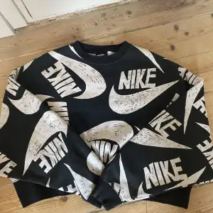 Svart sweatshirt med Nike tecken över hela tröjan. Änvänd några fåtal gånger men i nytt skick!