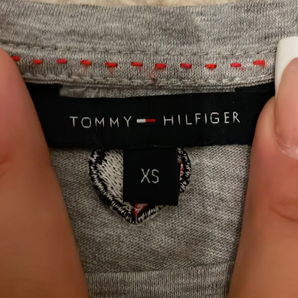 Säljer denna super vibiga Tommy Hilfiger tröjan/ toppen som jag har älskat, använd fåtal gånger. tröjan har även super fina hjärt detaljer, en framför och ett litet bakom nacken som man kan se i bild 3. Nyskick i ljus grå färg. 💕💕. T-shirts.