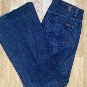 Lågmidjade mörkblå jeans - Säljer dessa snygga bootcut jeans från 7 for all mankind! Sprättade längst ner i benen för att göras längre. Midjemått 84cm och passar i perfekt i längden på mig som är 173. 