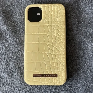 Mobilskal - Ett gul-mönstrat mobilskal från Ideal of Sweden. Endast använd fåtal gånger. Säljer då jag ej har en iPhone 11 längre. 
