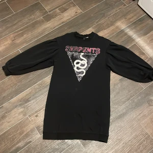 Klänning  - Svart klänning med tryck och korta ärmar, från H&M. Använd fåtal gånger.