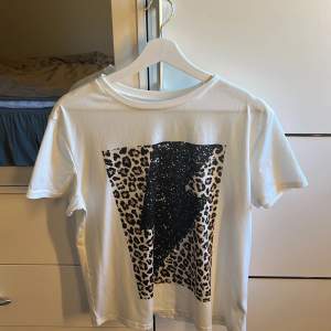 En vit T-shirt med leopard mönster och en svart blixt i mitten💗