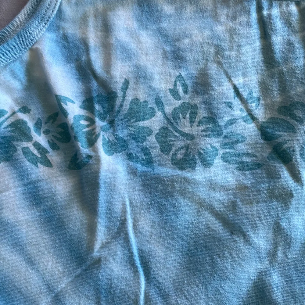Blått linne med blommor på. T-shirts.
