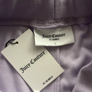 Lila juicy byxor  - Säljer dessa helt oanvända juicy byxor i storlek S❤️ de ser gråa ut på bilden men de är lila!💜 aldrig använda och lappen sitter kvar!!! Denna modellen har inga fickor där bak🫶🏼