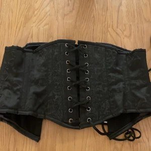 Svart Midje Korsett - En svart midje kortsett, köpt för ca två och ett halft år sedan. I bra skick och använd endast en gång. Kostade 700kr vid original köp.