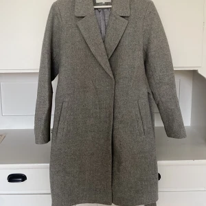 Grå kappa från Vila strl 36 - En grå varm kappa från vila. I använt men mycket fint skick och endast torr tvätt som rekommendation. Några få fläckar på insidan av jackan. Storlek 36