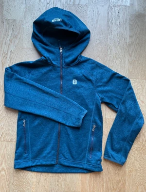 Fleece Mellanlager, stl 140 - Melerad petrol färgad tunnare fleece, luva, fickor med dragkedja. Justerbar nederkant I nyskick!  Från djurfritt och rökfritt hem 