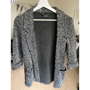 Stickad kofta - Grå blazer liknande kofta i nyskick. Trekvarts arm. 