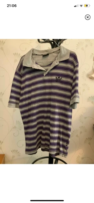 Adidas kortärmad tröja - Fin lila och grårandig kortärmad tröja från Adidas. Storlek M.