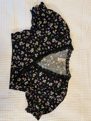 H&M topp storlek 36 - Kort svart topp med blommar från H&M, knappt använd. Bra skick