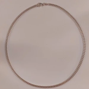 Kedjehalsband - Ett kedjehalsband i 925 silver, som syns på sista bilden. Sparsamt använd! Nypris cirka 1 100 kr. Skicka för fler bilder och frakt ingår. Längd: 50 cm Bredd: 4,1 mm Höjd: 2 mm.  Säljer för den inte kommer till användning.