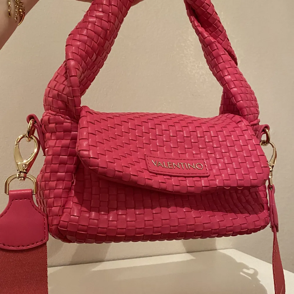 Väska från Valentino. Knappt kommit till användning så den är som ny. Fina guldiga detaljer och i fin stark rosa färg. Inköpt för 1445:- på Zalando. Väskor.