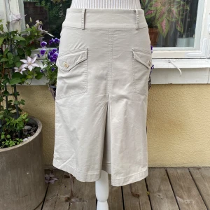 Beige midi kjol - GANT - En high-waisted midi kjol köpt second hand i Stockholm. Det är lite svårt att få upp dragkedjan pga ett hål där. Annars finns det inga fläckar eller hål. Därför är kjolen i gott skick. 