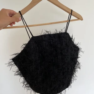 Svart fest topp - En svart fluffig fest topp med lite små glitter i. Dragkedjan i ryggen.  Från Ginatricot, storlek 36, frakt tillkommer.