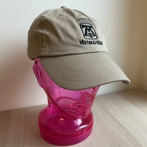 Keps - Ta din outfit till nästa nivå med denna beigea keps med tryck. Passar alla outfits oavsett sol, regn eller åska! Kom och köp, kom och köp! 