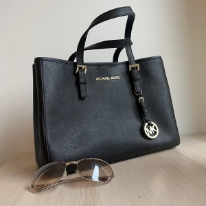 Michael Kors Väska - Säljer min mammas äkta Michael Kors väska som aldrig riktigt kom till användning. Nypris 2500kr men hon vill sälja den för 950kr då hon tycker om att hjälpa folk ❤️  30cm längd, 22cm höjd, 8 olika fack inuti