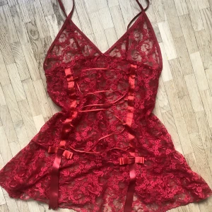 Kattig röd spets neglige klänning - Väldigt fin genomskinlig röd neglige med söta rosetter som kan användas både som underkläder och utomhus kläder! Tyvärr är den för liten för mig :/  kan frakta men möts helst upp i Stockholm 