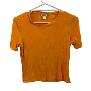 Fin orange T-shirt från Monki i storlek M men passar även mig lite löst (XS). köptes för många år sedan men är i super bra skick! Skulle dock behöva strykas men har ingen strykmaskin… (97% viskos, 3% Elastan)