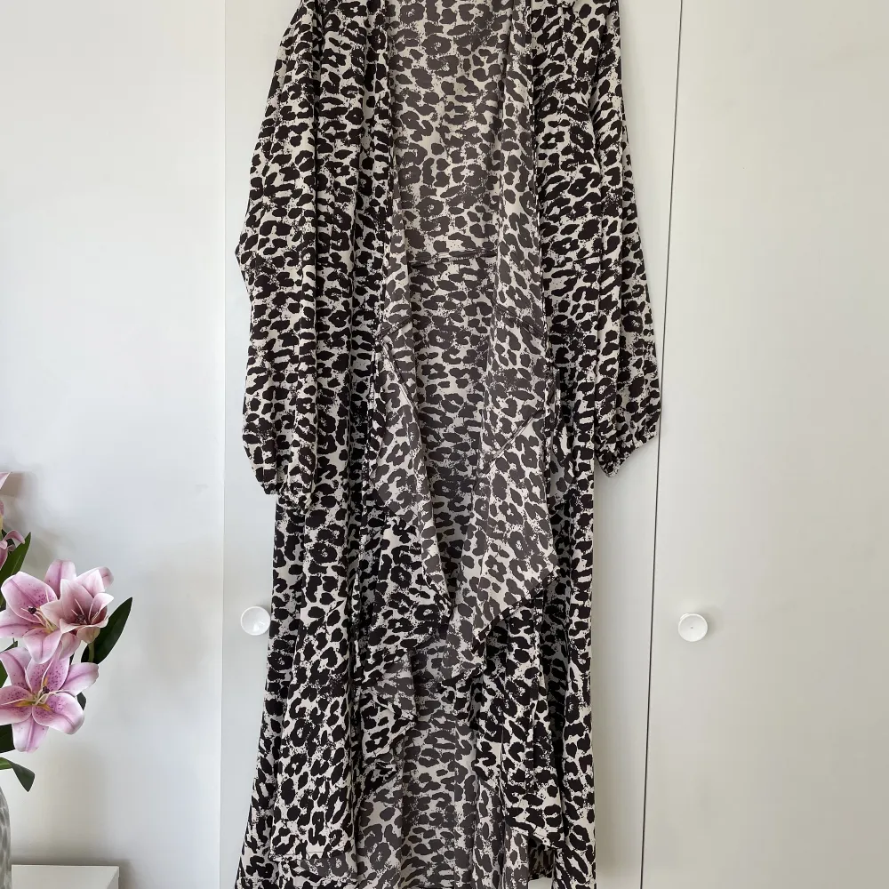 Lång leopardklänning med omlott och volang. Klänningen har långärm. . Klänningar.