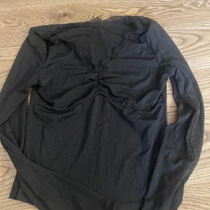 svart tröja - en svart tröja med spets runt och scrunch vid bröst partiet 