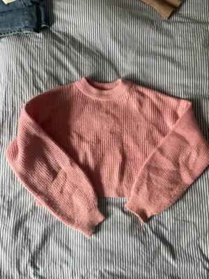 Stickad tröja - En gullig rosa stickad tröja. Väldigt mysig och fin att ha till exempelvis ett par jeans. Modellen är croppad.