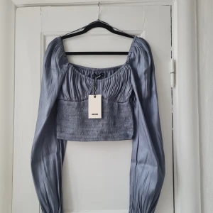 Topp - Topp i glansigt material från Bik Bok. Stora ärmar och söm under bysten. Nypris 399 kr